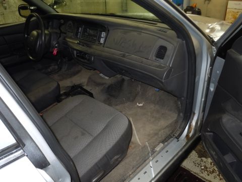 2001 Ford Crown Victoria - The interior of the vehicle shows signs of wear and tear, with a dusty dashboard and worn seats.