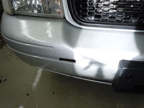 2001 Ford Crown Victoria - Close-up of the front bumper and grille of a silver 2001 Ford Crown Victoria, showing water droplets on the bumper.