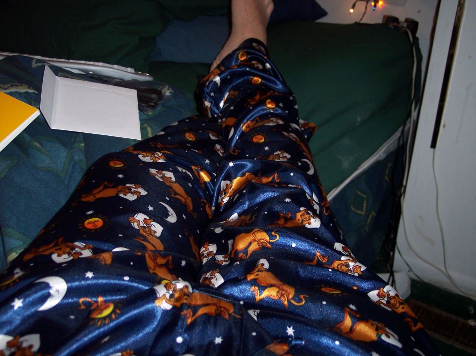 Person in blue pajamas with Scooby-Doo characters and celestial bodies, lying on a bed
