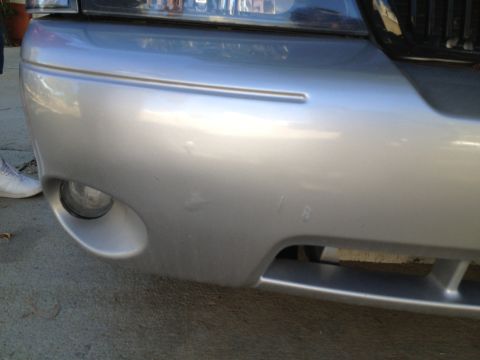1998 Ford Crown Victoria - Front bumper of a silver car, showing a fog light and minor damage.