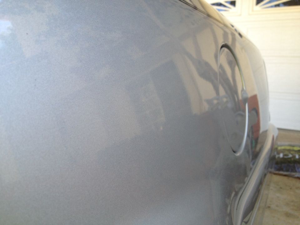 Close-up of a silver car's rear quarter panel and fuel filler door