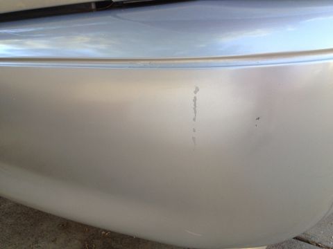 1998 Ford Crown Victoria - Close-up of a silver car bumper with visible scuff marks and imperfections.