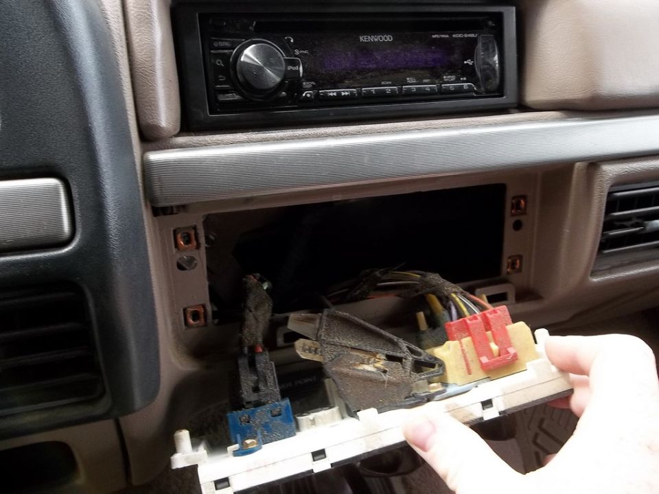 Car interior dashboard with a Kenwood stereo and exposed wiring from a removed panel