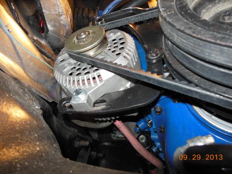 1979 Ford F-150 - Close-up view of an alternator and engine components, showing the drive belts and a blue painted engine block.