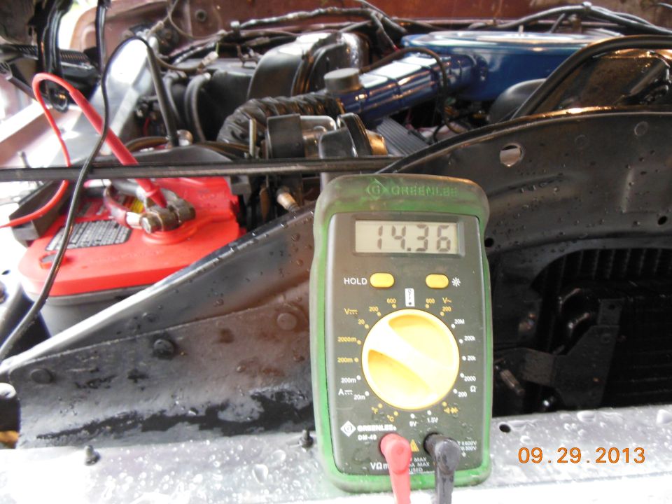 1979 Ford F-150 engine bay with multimeter reading 14.36V next to red battery