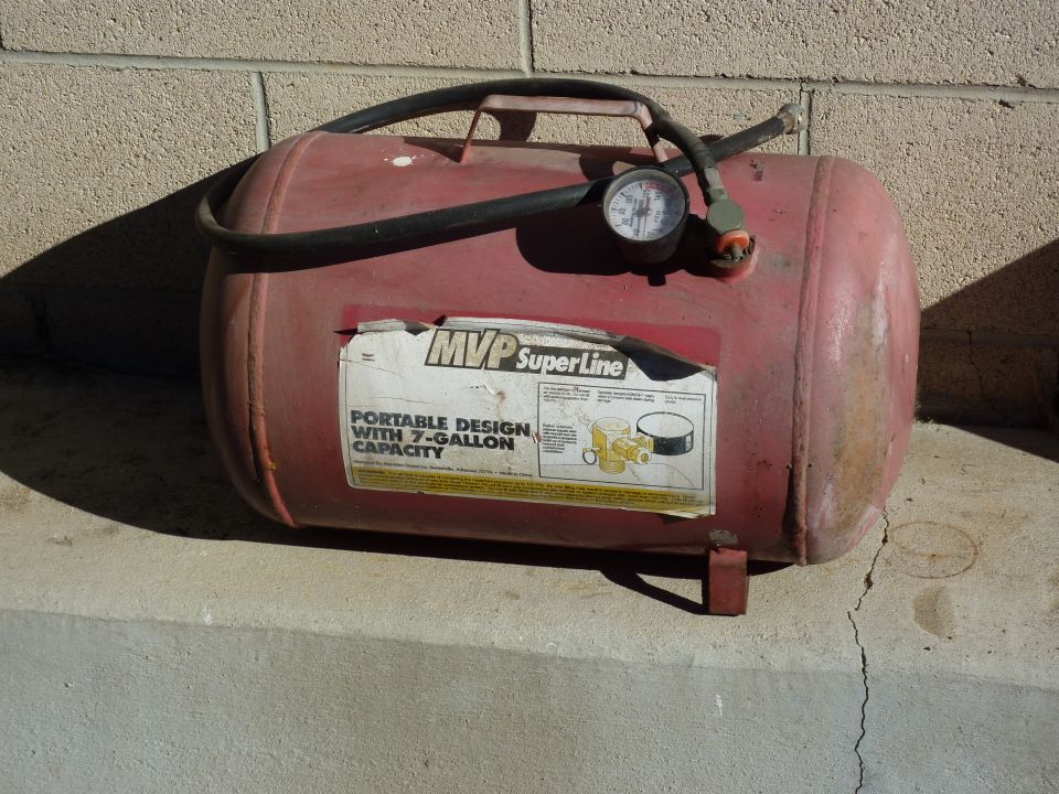 Red portable air compressor tank with a gauge and hose, labeled MVP SuperLine with 7-gallon capacity