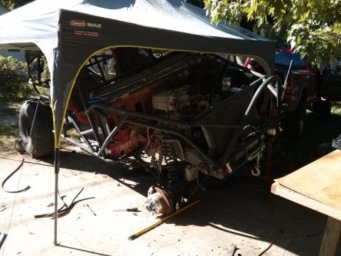 1986 Ford Bronco - This heavily modified off-road buggy is undergoing work, with its chassis and engine components exposed beneath a canopy.