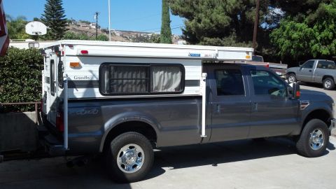 2000 Ford F-250 - A dark gray Ford F-250 Super Duty truck is equipped with a white camper shell.