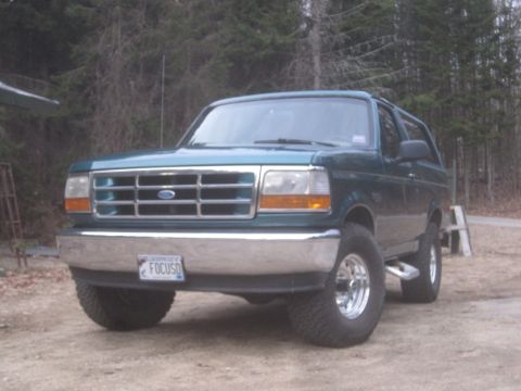 1996 Ford Bronco - A green 1996 Ford Bronco is parked outdoors with a chrome grille and bumper.