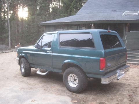 1996 Ford Bronco - This 1996 Ford Bronco is seen in a three-quarter rear view, parked on a dirt lot next to a house.