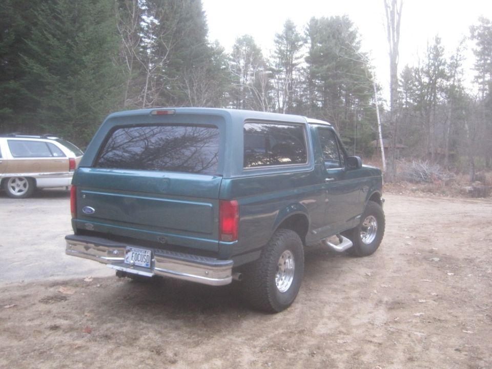 Green Ford Bronco SUV parked outdoors, with another vehicle partially visible to the left