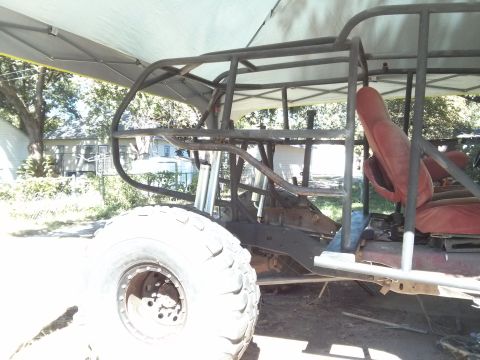1986 Ford Bronco - This custom-built off-road vehicle features a prominent roll cage and large tires, with red seats visible inside.