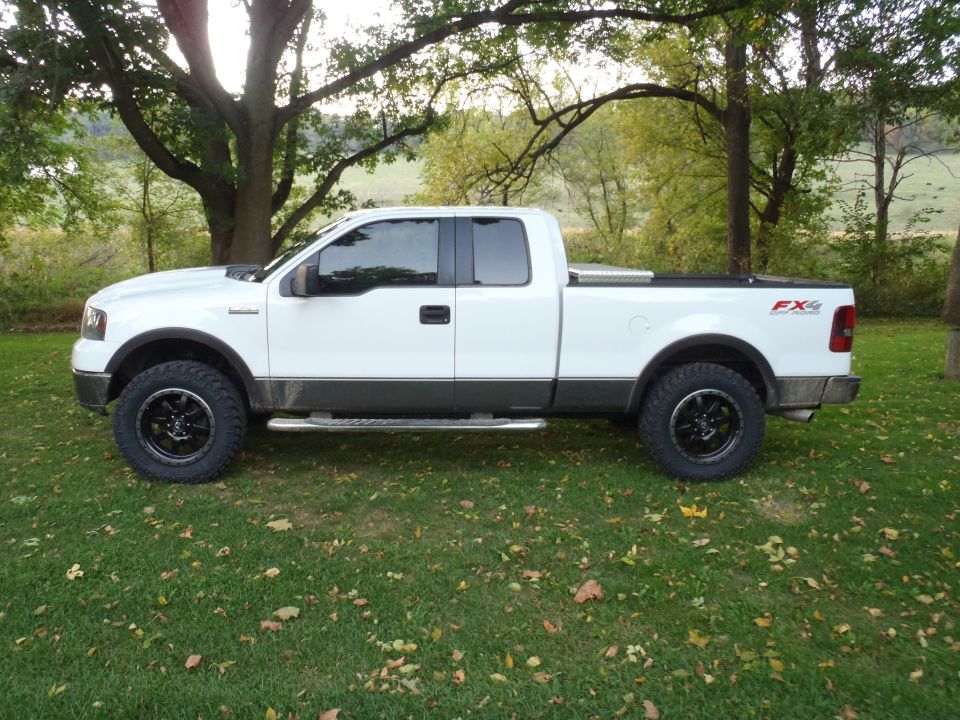 White 2006 Ford F-150 SuperCrew FX4 pickup truck parked on grass with trees in background