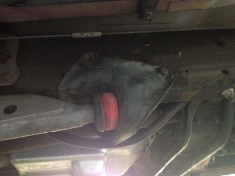 1992 Ford F-150 - A close-up view of a vehicle's suspension component, showing a red bushing and wiring conduit.