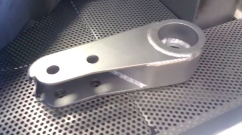 1996 Ford Bronco - A metal steering component with visible welds and bolt holes is shown in detail.