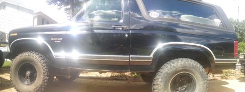 1986 Ford Bronco - This black Ford Bronco, likely from the early 1980s, is shown from the side with off-road tires.