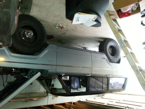 1982 Jeep Wagoneer - The side profile of a Jeep Grand Wagoneer is visible in a garage setting, with a ladder and storage boxes in the background.