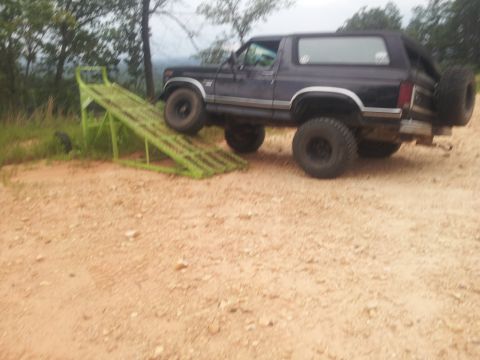 1986 Ford Bronco - Ford Bronco is positioned on a green ramp outdoors on a dirt path.