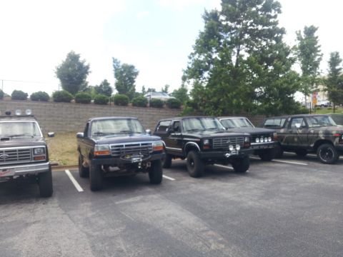1986 Ford Bronco - Several Ford Broncos are parked in a lot, some with modifications.