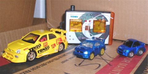 1990 Ford Bronco - Three remote-controlled toy cars and their controller are displayed on a cardboard surface.