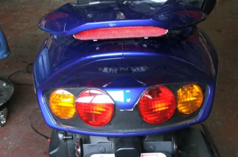 2006 Honda Reflex - The rear of a blue scooter shows its taillight assembly and a Honda emblem.