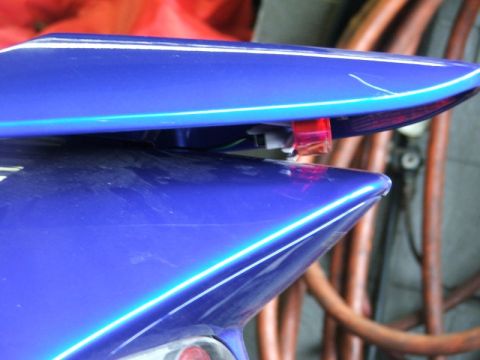 2006 Honda Reflex - Close-up of a blue scooter's tail light assembly, white pinstripes and a visible red light component.