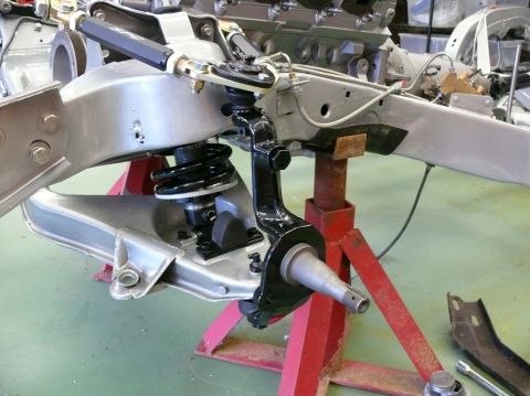 Front suspension assembly on red jack stands, with engine block in background