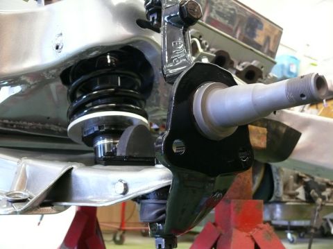 Close-up of a car's front suspension assembly, showing a shock absorber and steering knuckle