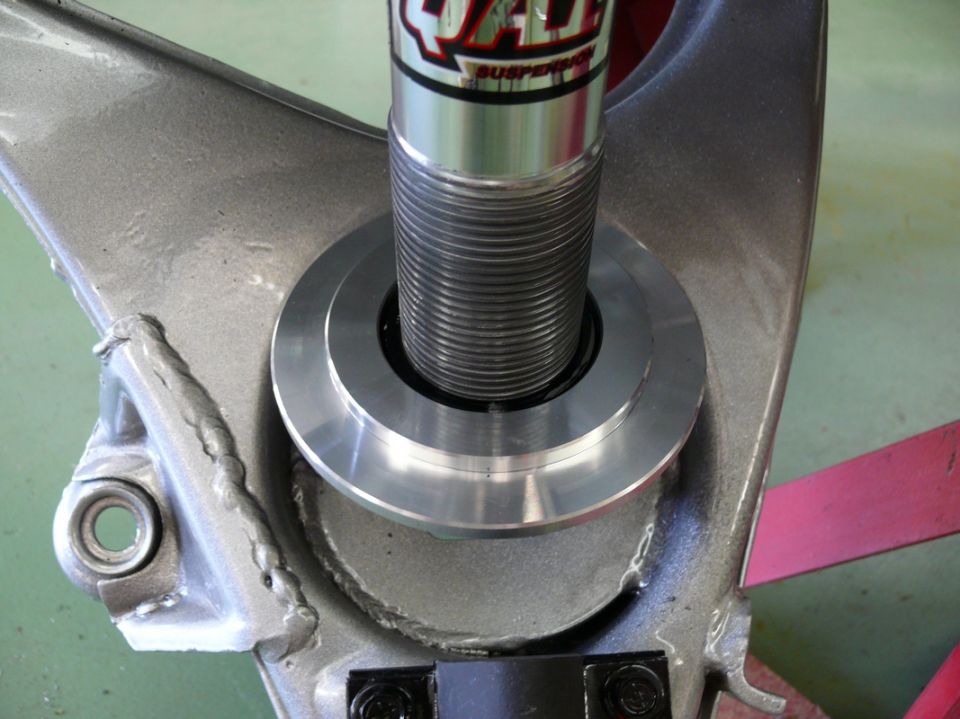 Close-up of a suspension component with a coilover shock absorber. Text on the shock reads 'QA1 SUSPENSION'