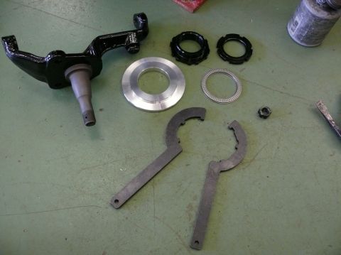 Corvette C3 spindle, bearing races, and spanner wrenches on a green surface