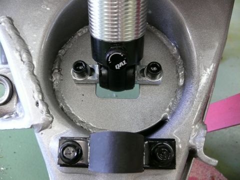 Shock absorber assembly with QAI branding, silver and black, bolted to gray metal frame