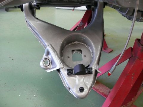 Close-up of a vehicle's suspension control arm assembly, supported by red jack stands