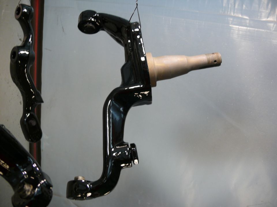 Black painted suspension part hanging, showing a spindle and mounting points