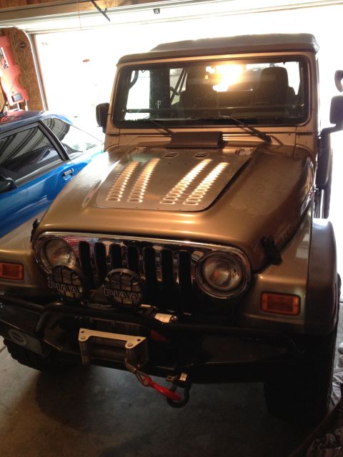 2005 Jeep Wrangler - Front view of a 2005 Jeep Wrangler parked in a garage, showing its grille, hood, and winch.