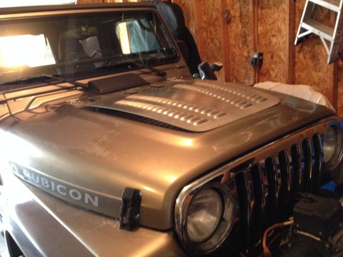 2005 Jeep Wrangler - The hood of a gold Jeep Wrangler, identified as a 2005 model, is visible with "Rubicon" badging.