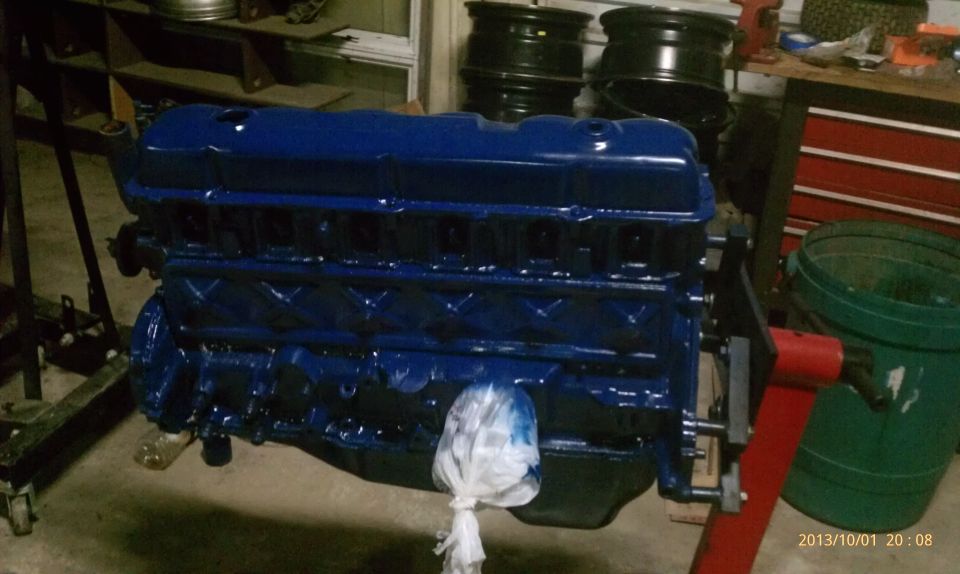 Freshly painted dark blue inline-six engine on a stand in a garage workshop
