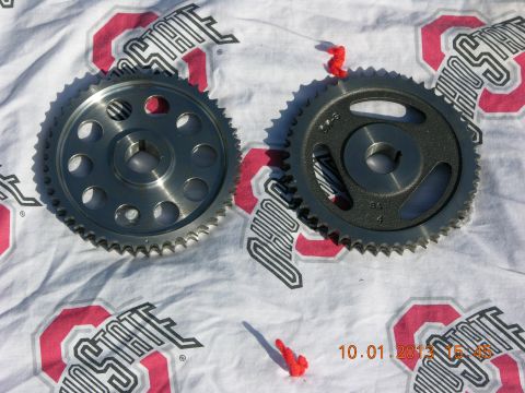 1969 Ford Fairlane - Two camshaft sprockets are shown on a cloth. One is silver, the other is dark gray with markings.
