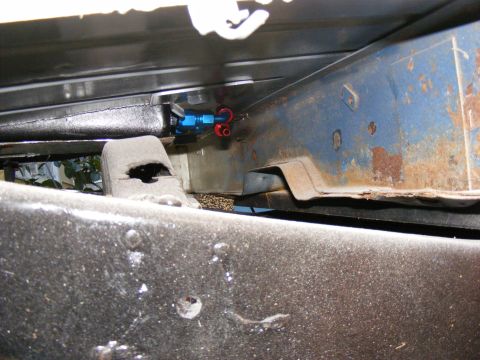 Underbody chassis with blue and red fuel lines attached to a metal bracket