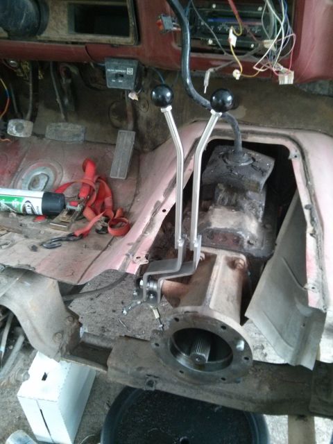 1986 Ford Bronco - The interior of a vehicle is shown with the transmission tunnel exposed, revealing shifter levers and transfer case parts.