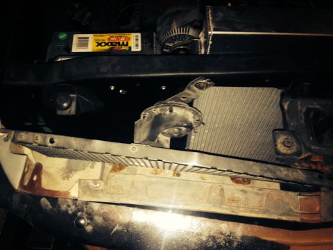 1965 Ford Mustang - Close-up view of a car's engine bay components, including the radiator and battery, with visible signs of wear.