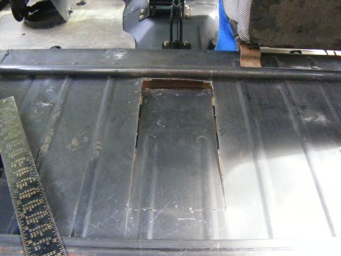 Metal floor panel with cut-out and ruler, viewed from above