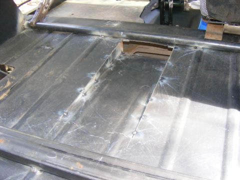 Vehicle floor pan showing welded metal patches and roll bar supports