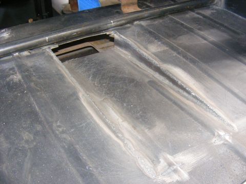 Metal floor pan with visible welds and a rectangular cutout