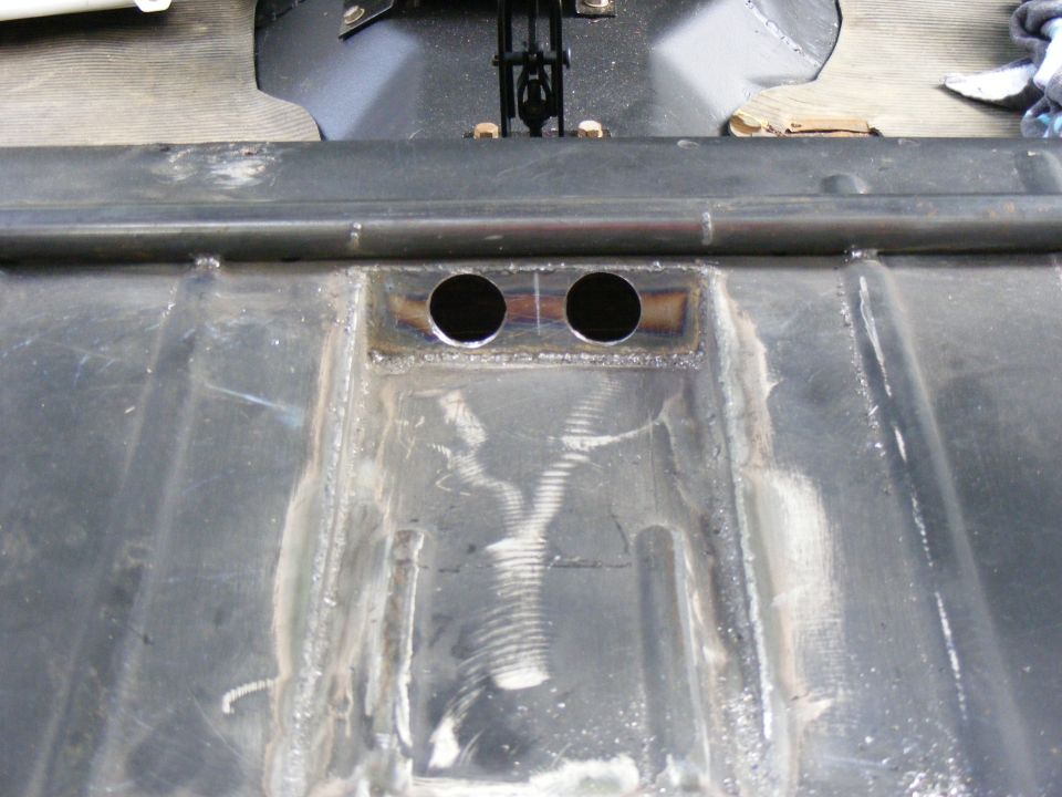 Underbody of a vehicle showing two circular holes and metal bracing
