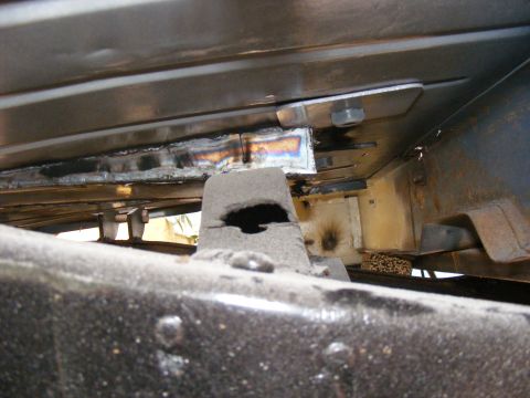 Underbody view of vehicle frame with visible welds and suspension parts