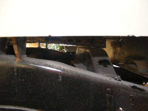 Close-up of a vehicle's frame and suspension components, showing rust and dirt