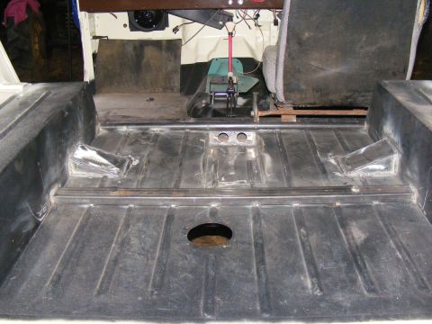 Vehicle interior floor with black coating, metal reinforcements, and a circular hole