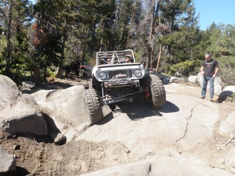 1961 International Scout 800 - A modified 1961 International Scout 800 navigates a challenging rocky terrain with other vehicles in the background.
