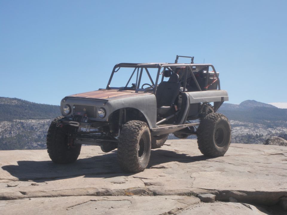 1961 International Scout 800 modified for off-roading, with a roll cage and large tires, parked on a rocky surface