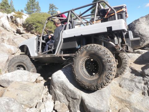 1961 International Scout 800 - Custom off-road buggy with a prominent roll cage navigating a difficult rocky terrain.